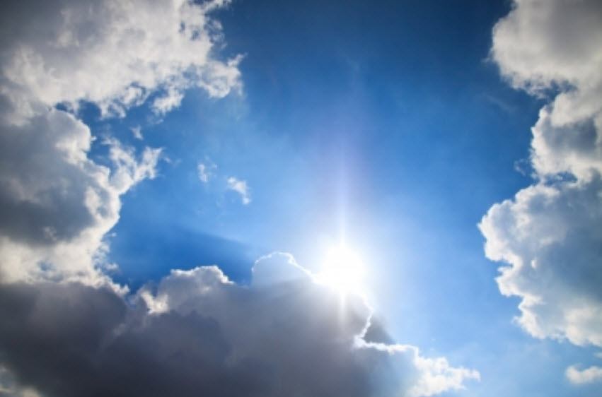 The sun is shining through the clouds in the sky